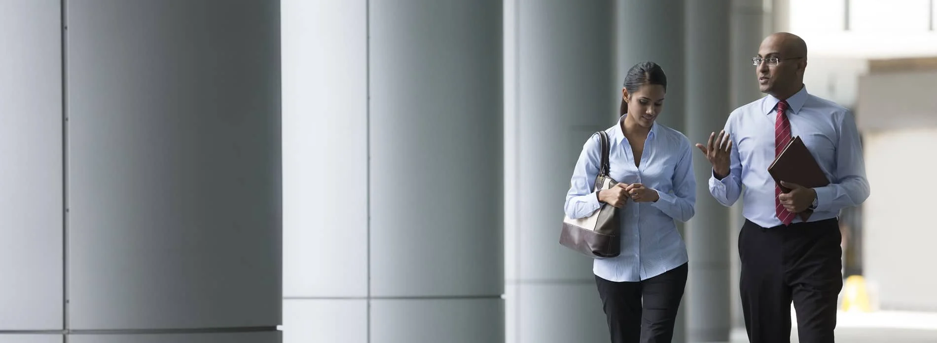 man and woman walking and talking through office corridor